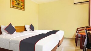 Ein Hotelzimmer mit Bett, Schreibtisch mit Stuhl, Klimaanlage und einem Bild an der Wand.