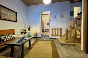 Ein Wohnzimmer mit Sofa, Couchtisch, Treppe und einem Flur, der in einen anderen Raum führt.