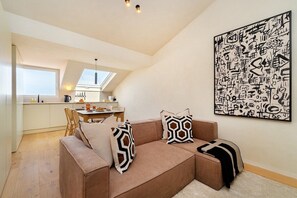 A modern interior with a sofa, geometric pillows, a dining area, and a kitchen. - Modern Studio for Easy Everyday Living (Lisbon)