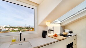 A modern kitchen with a large window, a sink, a kettle, and a cutting board with oranges. - Modern Studio for Easy Everyday Living (Lisbon)