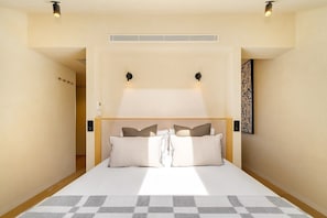 A bedroom with a bed, bedside lamps, a wall-mounted artwork, and a ceiling vent. - Modern Studio for Easy Everyday Living (Lisbon)