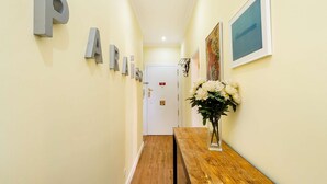 A hallway with a wooden bench, a door with a sign, and a framed picture on the wall. - Sunny Terrace Apartment w/ River Views (Lisbon)