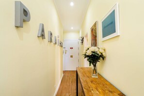 A hallway with a wooden bench, a door with a sign, and a framed picture on the wall. - Sunny Terrace Apartment w/ River Views (Lisbon)