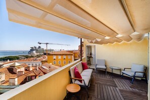 A balcony with a view of a cruise ship, a construction crane, and traditional buildings. - Sunny Terrace Apartment w/ River Views (Lisbon)