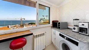 A kitchen with a view of the sea, a washing machine, a microwave, and a toaster. - Sunny Terrace Apartment w/ River Views (Lisbon)