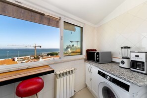 A kitchen with a view of the sea, a washing machine, a microwave, and a toaster. - Sunny Terrace Apartment w/ River Views (Lisbon)