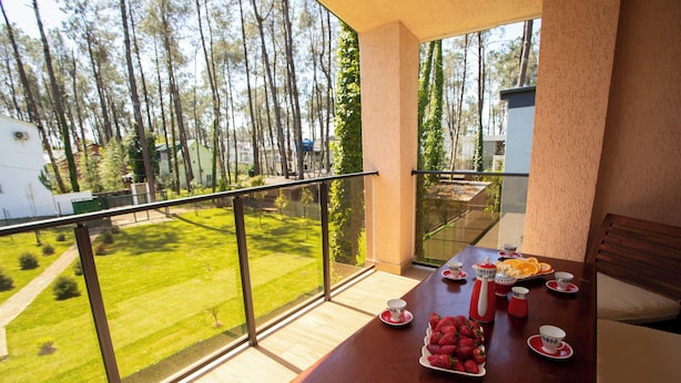 A balcony with a table set for breakfast, a view of a green landscape, and a clear sky. - 3-bedroom Family Paradise Villa in Woods (Magnetiti)