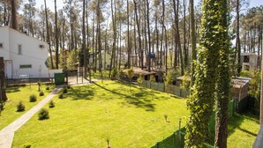 A residential area with a white building, a grassy yard, and a tall tree with ivy. - 3-bedroom Family Paradise Villa in Woods (Magnetiti)