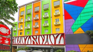 A multi-story hotel with balconies, a signboard, and parked cars. - Cozy Double Escape W/ Free WiFi and Parking (Jakarta)