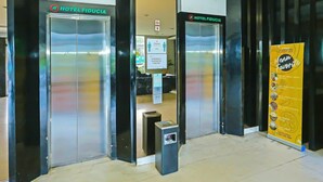 A hotel entrance with two elevators, a physical distancing sign, and a menu advertisement. - Cozy Double Escape W/ Free WiFi and Parking (Jakarta)
