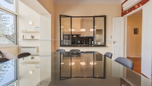 A modern dining area with a glass table, chairs, and pendant lights. - Spacious Mordern Apt in Graça’s Historic Quarter (Lisbon)