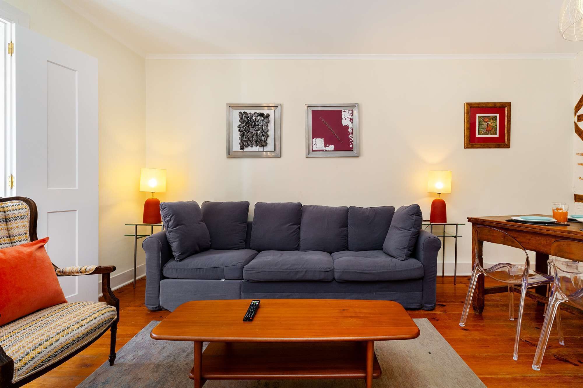 Ein Wohnzimmer mit grauem Sofa, einem Holztisch und zwei Wandleuchten.