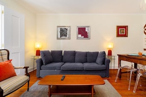 Ein Wohnzimmer mit grauem Sofa, einem Holztisch und zwei Wandleuchten.