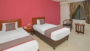 A hotel room with two beds, a chair, a small table, and a window with curtains. - Luxury Twin Stay with Free WiFi and Parking (Jakarta)