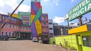 A hotel with a colorful facade, a prominent sign, and a parking area. - Luxury Twin Stay with Free WiFi and Parking (Jakarta)