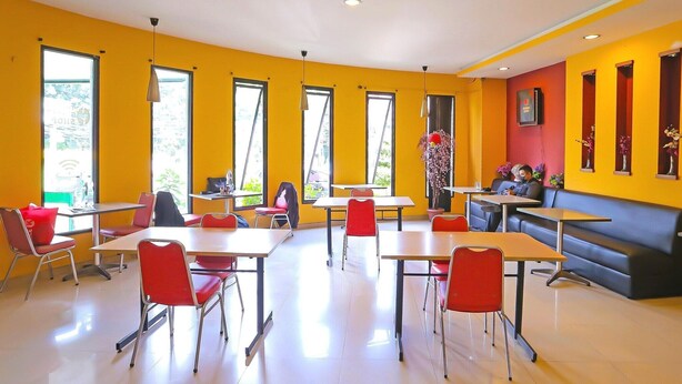 A bright room with yellow walls, large windows, and red chairs around tables. - Luxury Twin Stay with Free WiFi and Parking (Jakarta)
