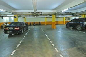 Eine mehrgeschossige Parkgarage mit Fahrzeugen auf verschiedenen Ebenen, sichtbaren Stahlträgern und einer Decke mit freiliegenden Rohren.