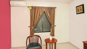 A room with a window, a chair, a small table, and an air conditioning unit. - Luxury Twin Stay with Free WiFi and Parking (Jakarta)