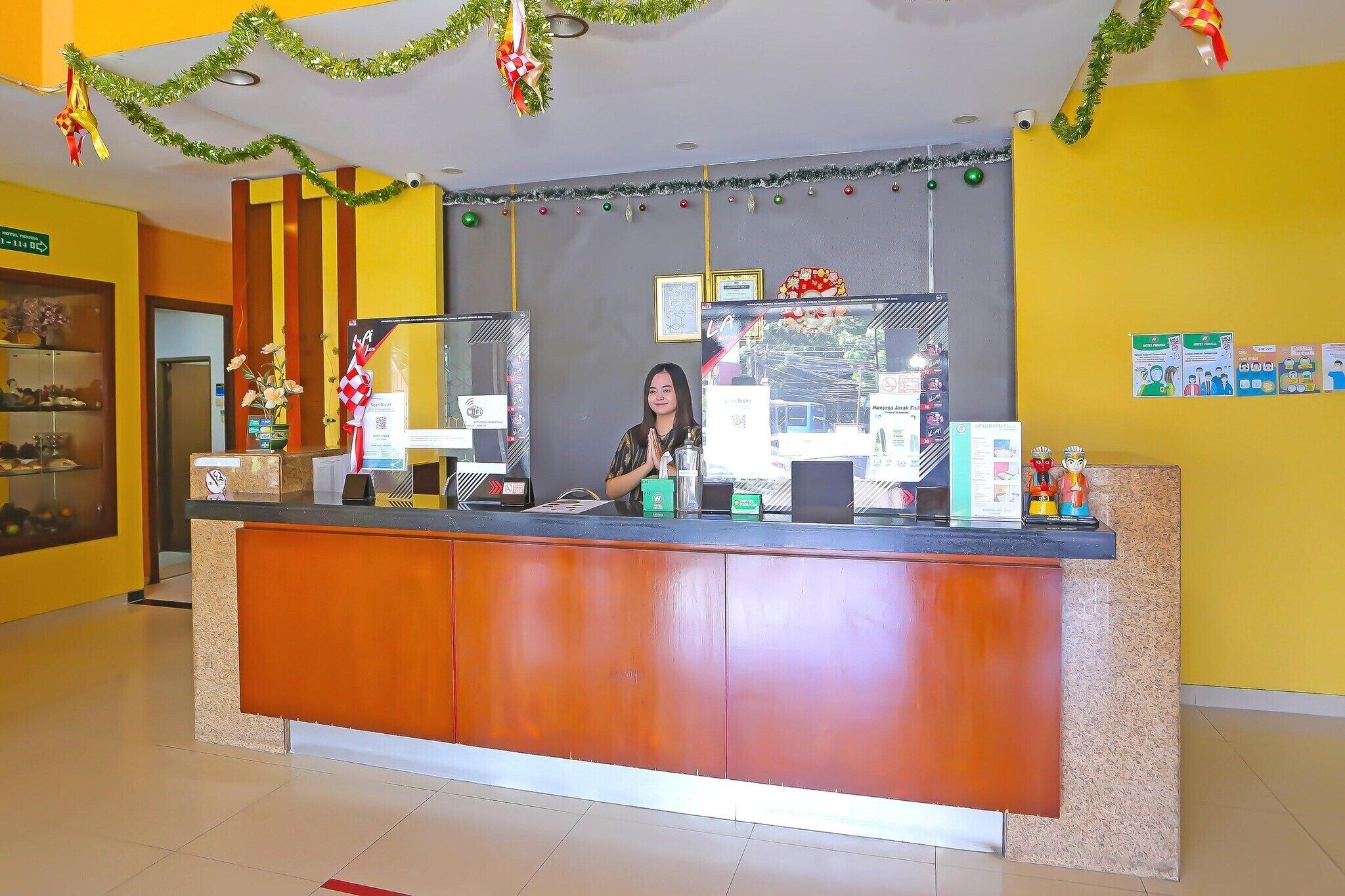 A reception desk with a woman behind it, a framed picture, and a sign with a QR code.