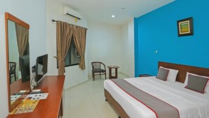 A hotel room with a bed, a desk with a computer, a chair, a small table, and a window with curtains. - Stylish DBL Suite Escape W/ Free WiFi and Parking (Jakarta)