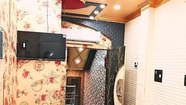 A hotel interior with a decorative ceiling, a television, and a patterned wall. - Atharv Paying Guest House (Varanasi)
