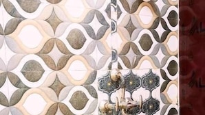 A bathroom with a patterned tile wall, a white sink, and a shower with a faucet. - Atharv Paying Guest House (Varanasi)