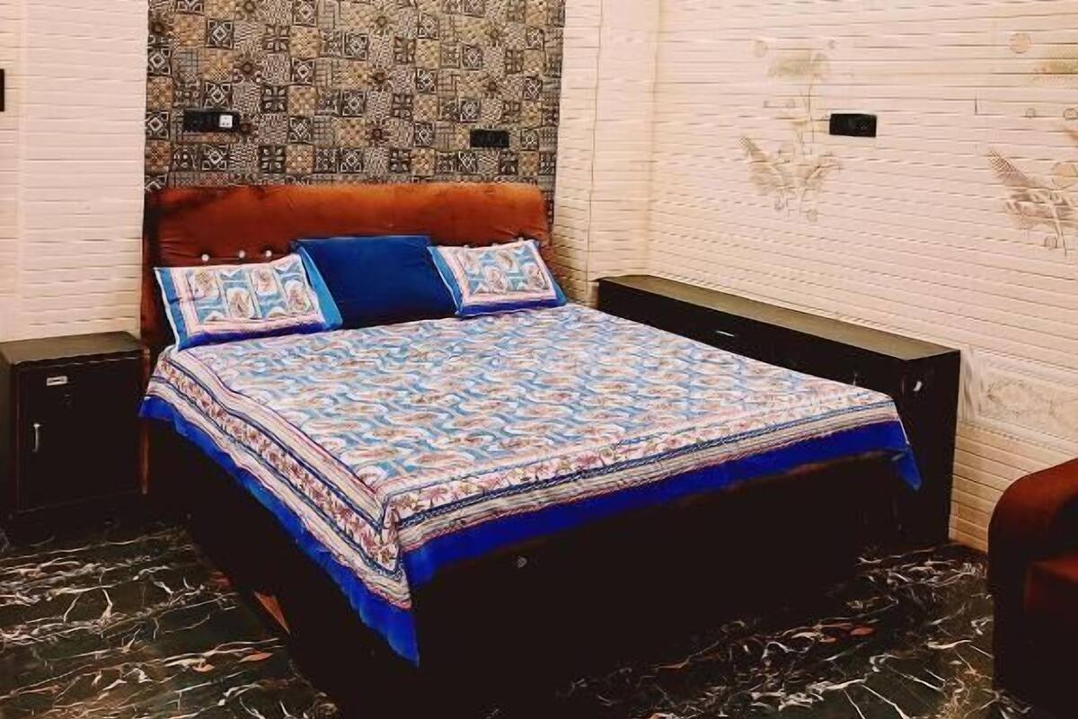 A bedroom with a patterned headboard, a bed with a blue and white bedspread, and a marble floor.