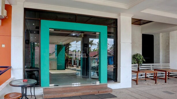 A building entrance with a glass door, steps leading up to it, and a small table and bench outside.
