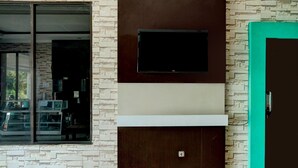 A modern interior with a large window, a flat-screen TV mounted on a wall, and a teal-colored door.