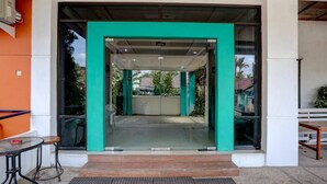 A hotel entrance with a glass door, a small outdoor seating area, and a view of the street.