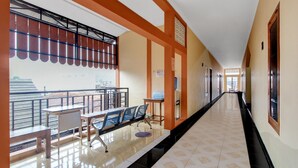 Un couloir d’hôtel avec un long banc, une table et des chaises le long du mur.