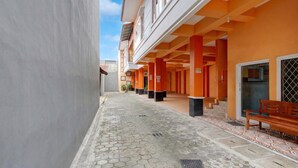 Un couloir avec un sol carrelé, des bancs et un bâtiment doté de piliers orange et d’une enseigne.