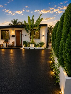 A modern house with a paved driveway, potted plants, and outdoor seating. - Waterfront Luxury Home Prime Location Near Hard Rock Stadium - Beach & Airport (Hollywood)