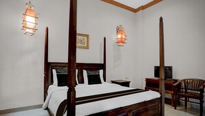 A four-poster bed with a wooden headboard, two bedside tables, a television on a wooden stand, and a wooden chair.