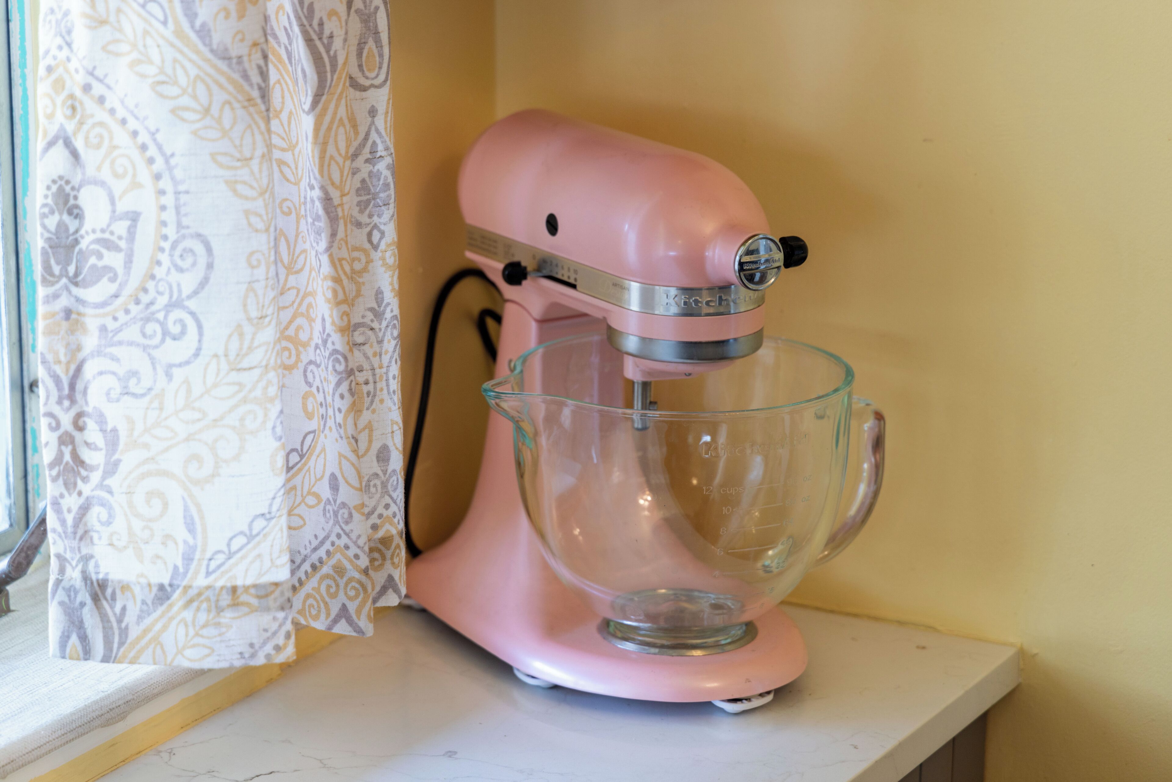 Un appareil de cuisine rose avec un bol en verre, posé sur un plan de travail.