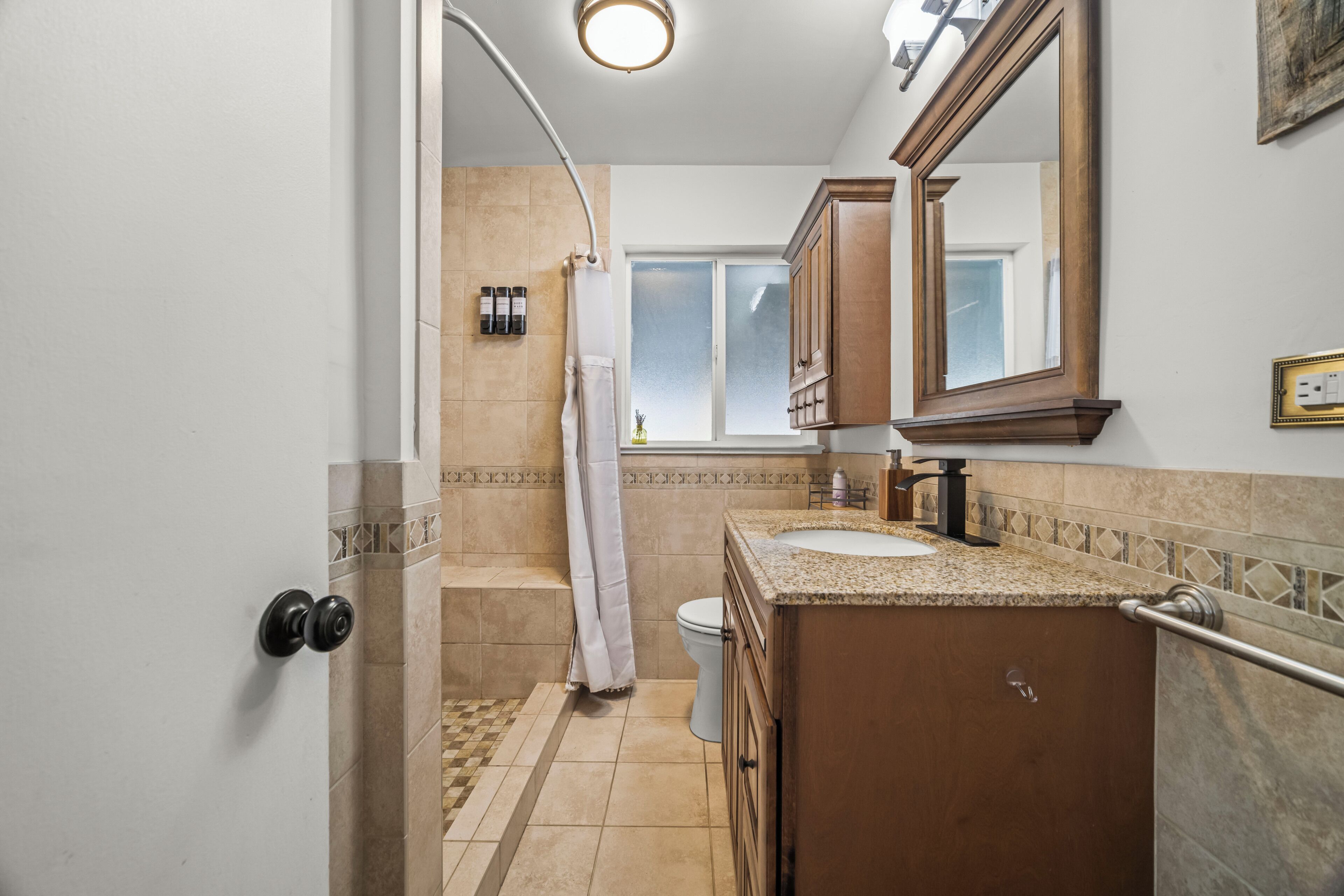 A bathroom with a shower, toilet, sink, and vanity.