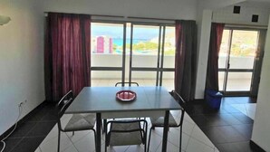 Un comedor con mesa, sillas y vistas amplias a través de grandes ventanales.