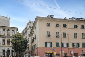 A multi-story building with a flat facade, green shutters, and a visible storefront with signage. - Cute Nest near the Center by Wonderful Italy (Genoa)