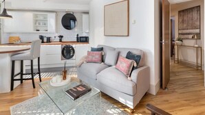 A modern living space with a sofa, coffee table, and kitchen area. - Modern Fulham 1-bedroom Apartment (London)