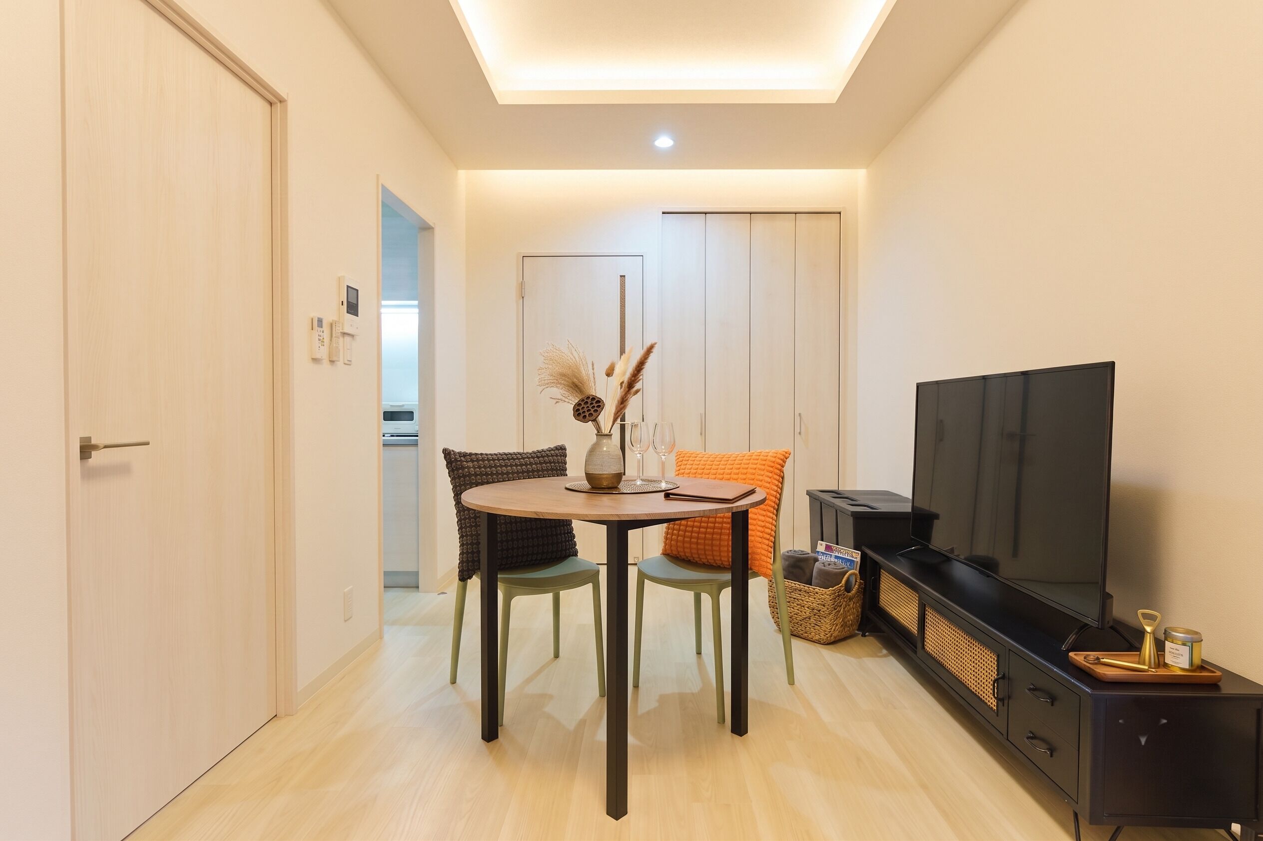 A compact living space with a dining area, a television, and a kitchenette.