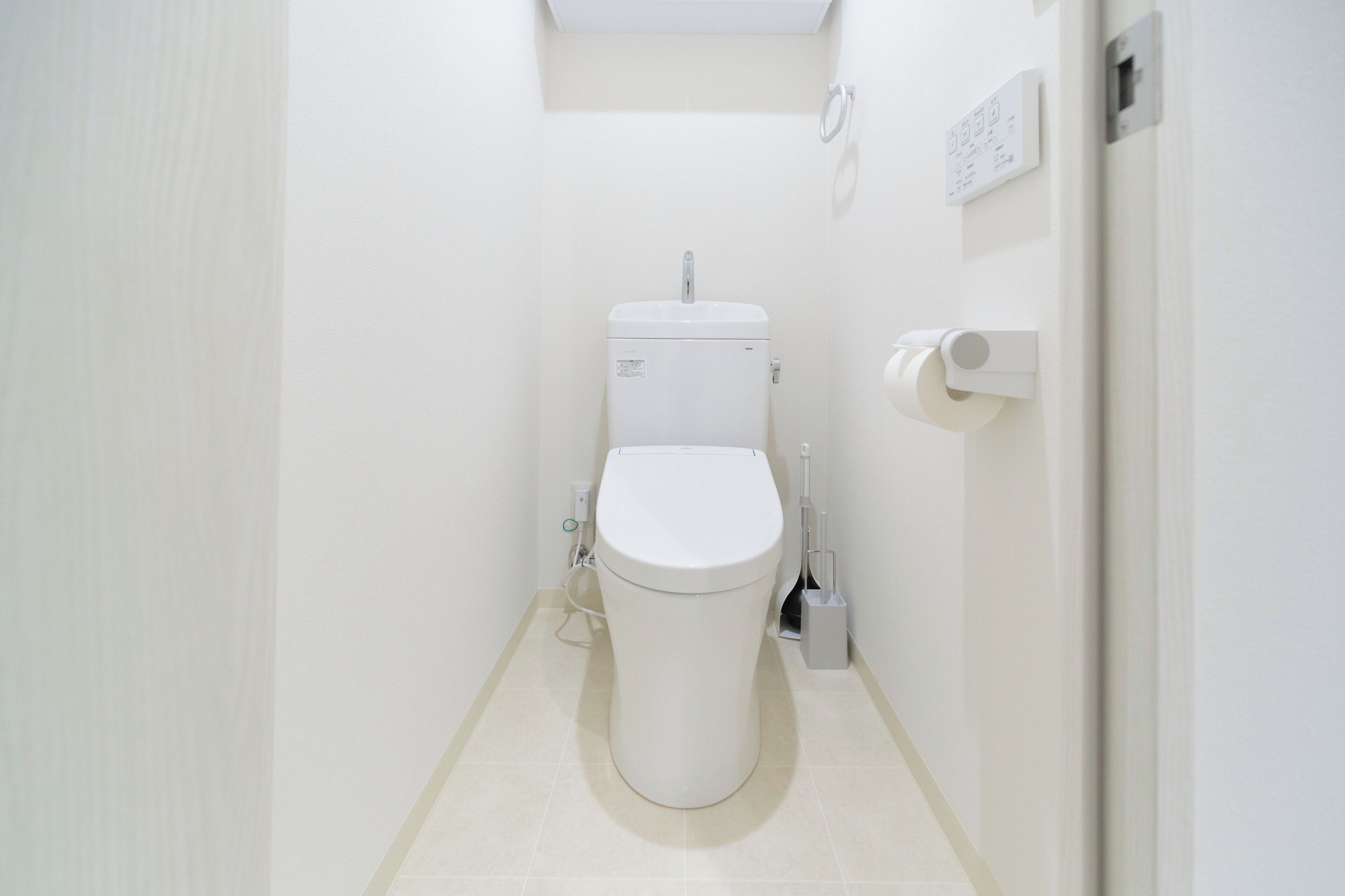 A small, white bathroom with a toilet, a bidet, and a toilet paper holder.