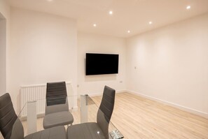 Ein Konferenzraum mit Glastisch, vier Stühlen, einem Wand-Fernseher und einem weißen Heizkörper.