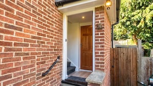 A brick exterior with a wooden door, a small porch, and a wooden fence. - Newly refurbished London base with Jubilee line on your doorstep (Greater London)