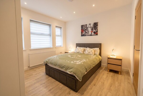 Ein Schlafzimmer mit Bett, Nachttischen, Heizkörper und Fenster.