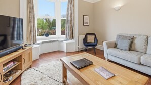 A living room with a television, a sofa, a coffee table, and a chair.