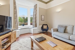 A living room with a television, a sofa, a coffee table, and a chair.