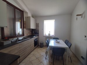 Eine kleine Küche mit Essbereich, Fenster und Heizkörper.