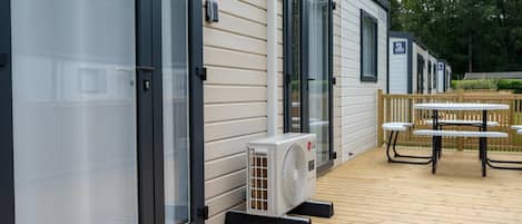 Een stacaravan met een terras, zitplaatsen buiten en een airconditioning.