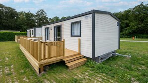 A mobile home with a deck, a window, and a door. - Comfortable caravan in a green setting (Lembeke (Kaprijke))
