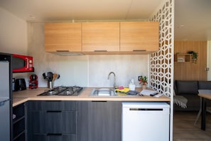 A compact kitchen with wooden cabinets, a gas stove, a microwave, and a dishwasher.